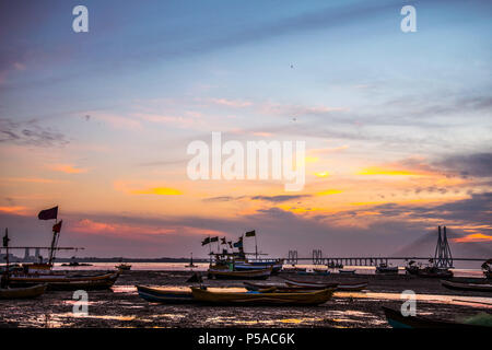 Silhouette der Fischerboote bei Ebbe, Sonnenuntergang in der Bucht von mahim - Mumbai, Maharashtra, Indien. Bandra worli Sea Link, Pali Hügel im Hintergrund. Stockfoto