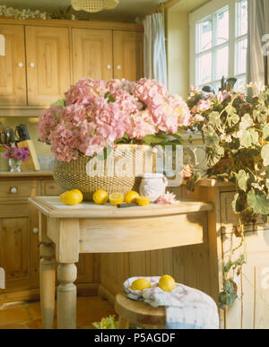 Rosa Hortensien in großen raffia Korb auf kleine vorhanden Tabelle im Land Küche Stockfoto