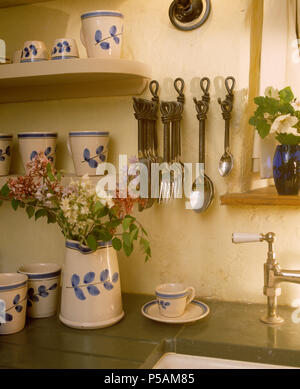 Metallgegenstände auf Wand Haken oben funktioniert Top mit Blau + weiß Blatt-gemusterten Kanne und Becher Stockfoto