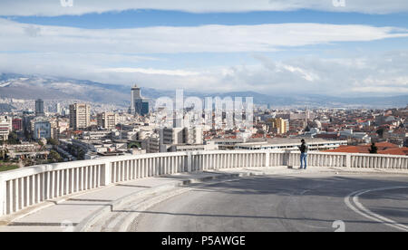 Izmir, Türkei - 12. Februar 2015: urban skyline mit modernen Gebäuden und Berge bei bewölktem Himmel. Normaler Mann beobachtet Stadt panorama Stockfoto