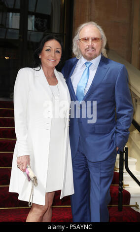 Sänger und Songwriter Barry Gibb, mit seiner Frau Linda, die im Buckingham Palace, London, wo er bei der heutigen Ordensverleihung zum Ritter geschlagen werden. Stockfoto