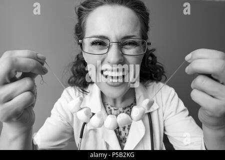 Lächelnd Kinderarzt Frau in Weißem medizinischen Robe mit Knoblauch Perlen auf Hintergrund Stockfoto