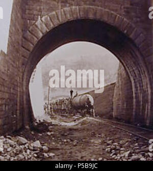 N/A. Deutsch: Das Bild zeigt eine pneumatische Lokomotive während der Bau des Gotthard Eisenbahntunnels hinter einem torbogen oder kurzen Tunnel von nur wenigen Metern verwendet. Der ursprüngliche Titel des Bildes führt zu 'Tunnel Eingang in Airolo", die vermutlich die ungefähre Lage der gezeigten Bogen, der ist nicht das südliche Portal zu den Gotthard Eisenbahntunnels selbst zeigt. Die gezeigten pneumatische Lokomotive gespeicherte Energie in Form von Druckluft in den grossen Druck Container bis vorne. Die freigegebene Luft erweitert wurde verwendet, um den Motor der Lokomotive zu betreiben. Dampf angetriebene Kompressoren w Stockfoto