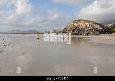 Eine Frau läuft entlang der leeren Sandstrand von Lettergesh Strand eines der vielen atemberaubenden Connemara Strände. County Mayo, Irland Stockfoto