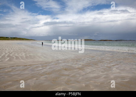 Eine Frau geht den herrlichen weißen Sandstrand von Glassilaun Beach in der Nähe von renvyle an der Küste von Connemara County Galway, Irland Stockfoto