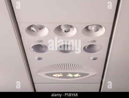 Verstellbare Lampen und Klimaanlagen overhead Sitz kontrolliert von einem kommerziellen Flugzeugen im Flugzeug mit Rauchverbot und Sicherheitsgurt auf Zeichen Stockfoto