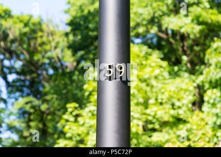 Hausnummer 59 Hausnummer auf der Pole 50 - neun in der Nähe der Bäume. Stockfoto