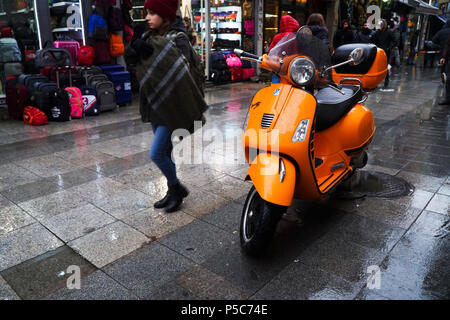 Istanbul, Türkei - 31. Dezember 2016: Details eines nassen orange Piaggio Vespa S in einer regnerischen Tag in Istanbul, Kadiköy. Ein junges Mädchen ist vorbei. Stockfoto