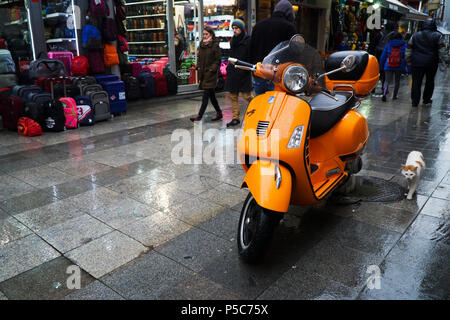 Istanbul, Türkei - 31. Dezember 2016: Details eines nassen orange Piaggio Vespa S in einer regnerischen Tag in Istanbul, Kadiköy. Einige Menschen sind zu Fuß unterwegs. Stockfoto