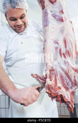 Metzger schneiden Stücke Fleisch von Schlachtkörpern Stockfoto