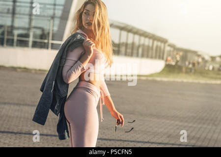 Porträt der jungen und schönen Frau in Freizeitkleidung in der Straße. In rosa Hemd und Hose bekleidet. Frühling, Sommer Konzept. Entspannen Zeit. Mädchen mit Stockfoto