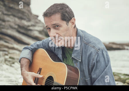 Mann an der Gitarre an der französischen Küste Stockfoto