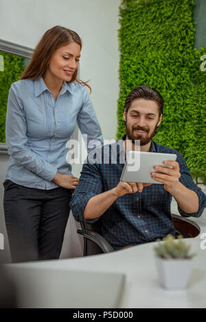 Clevere progressive junge Ingenieure arbeiten an digitalen Tablet auf einer ökologischen Bauvorhaben im Büro, reden über einige grüne Projekt. Stockfoto