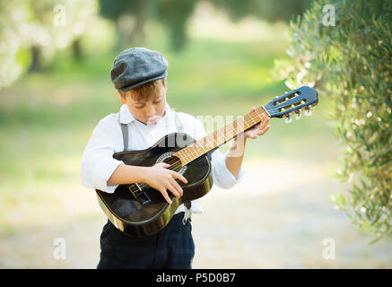 Jungen spielen auf der Gitarre zu Hause am sonnigen Tag. Stockfoto