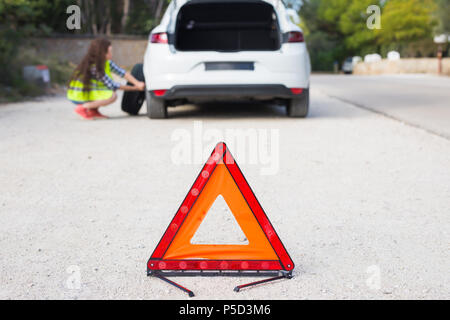 Die Frau hat das Auto, das Sie versucht, das Rad zu wechseln. Stockfoto