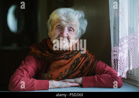 Portrait von einer älteren Frau zu Hause sitzen am Tisch. Stockfoto