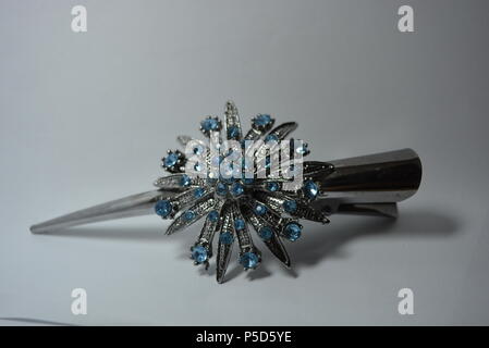 Schöner Damenschmuck, Stahl und eleganter Modeschmuck. Graue Metallhaarspange mit großer Metallblume aus blauen Steinen auf weißem Hintergrund Stockfoto