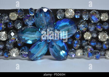 Damenschmuck, Stahl und eleganter Modeschmuck. Schwarzer Damengürtel mit elastischen Bändern, verziert mit abgeschrägten Einsätzen, blauen und weißen Steinen. Stockfoto