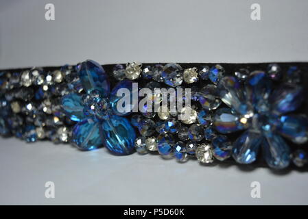 Damenschmuck, Stahl und eleganter Modeschmuck. Schwarzer Damengürtel mit elastischen Bändern, verziert mit abgeschrägten Einsätzen, blauen und weißen Steinen. Stockfoto