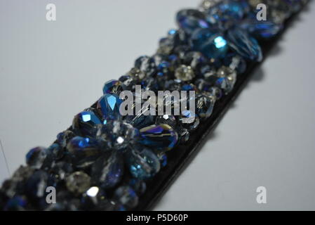 Damenschmuck, Stahl und eleganter Modeschmuck. Schwarzer Damengürtel mit elastischen Bändern, verziert mit abgeschrägten Einsätzen, blauen und weißen Steinen. Stockfoto