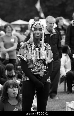 Candid monochromen Bild eines schönen junge schwarze Frau mit geflochtenem Afro Haar an der 2018 Afrika Oye Music Festival im Sefton Park, Liverpool. Stockfoto