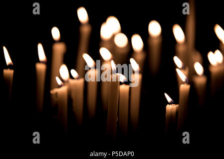 Viele brennende Kerzen - Licht der Kerzen in der Kirche auf dem schwarzen Hintergrund Stockfoto