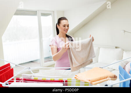 Frau, die Handtücher vom Wäscheständer zu Hause Stockfoto
