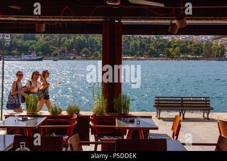 Chalcis, Griechenland - 10. Juni 2018: Blick über Cafe Windows von drei Mädchen zu Fuß entlang der Promenade in Chalcis, Griechenland Stockfoto