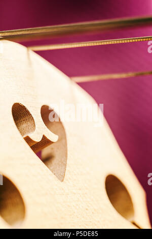 Details eines cello Bridge mit Streichern auf lila Hintergrund. Stockfoto