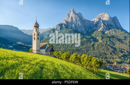 Panoramablick auf der idyllischen Berglandschaft der Dolomiten mit St. Valentin Kirche und berühmten Mount Schlern im schönen Morgenlicht bei Sonnenaufgang Stockfoto