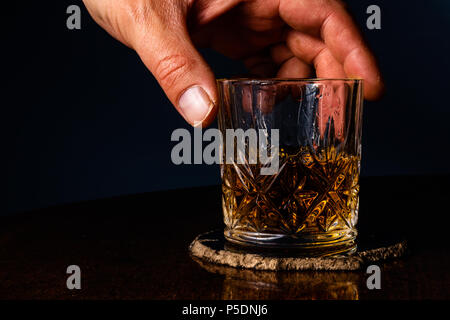 Eine Hand wieder ein Kristall Glas mit Whiskey gefüllt Stockfoto