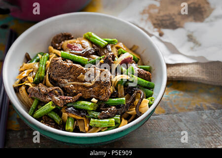 Wok gebratene Rindfleisch, grüne Bohnen, Pilze mit Reisnudeln Stockfoto