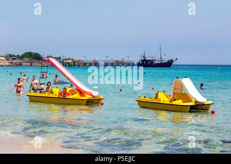 Urlauber schwimmen im Mittelmeer im Resort in der Nähe von Protaras, Ayia Napa, Zypern mit den Touristen Piraten der Black Pearl Schiff in der Rückseite Stockfoto