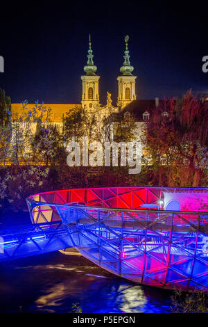 Schöne Panorama der berühmten Grazer Murinsel, eine künstliche schwimmende Insel in der Mitte der Mur bei Nacht beleuchtet, Graz, Steiermark, Stockfoto