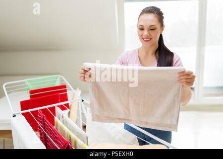 Frau, die Handtücher vom Wäscheständer zu Hause Stockfoto