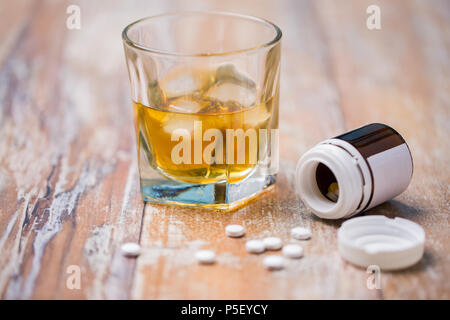 Glas Alkohol und Pillen auf Tisch Stockfoto