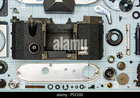 Teile sind vollständig demontiert alten retro Film SLR Kamera auf Millimeterpapier, close-up Stockfoto
