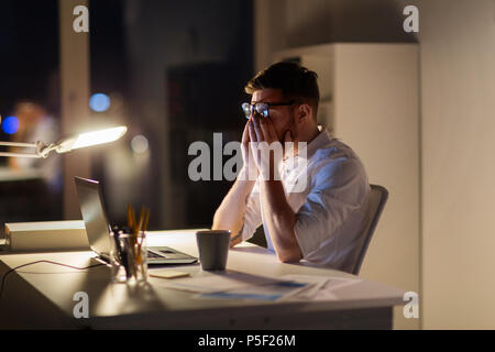 Müde Geschäftsmann mit Laptop in der Nacht Büro Stockfoto