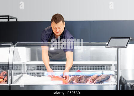 Männliche Verkäufer mit Meeresfrüchte in Fish shop Kühlschrank Stockfoto