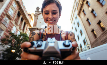 Nahaufnahme von einem lächelnden Frau, Tourist, Foto in eine Kamera. Low Angle Shot einer Frau unter Foto draußen mit Gebäude im Hintergrund Stockfoto