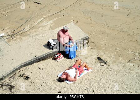 Ältere Menschen fettleibig Paar Sonnenbaden am Strand von Cornwall an einem Sommertag, Cornwall, England, Großbritannien Stockfoto