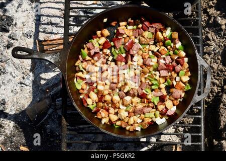 Pfanne braten Würstchen, Paprika, Kartoffeln und Zwiebeln in einem Wald Lagerfeuer draußen an der blutigen See Rendezvous, Wisconsin, USA Stockfoto