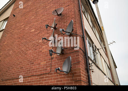 Array von alten und neuen Satelliten-TV-Empfänger Gerichte auf der Wand einer Wohnung mehrfamilienhaus Maryport Cumbria England Großbritannien Stockfoto