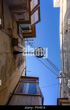 Beleuchtung und elektrische Leitungen oberhalb der engen Gassen in der Altstadt von Victoria, Gozo, Malta. Stockfoto