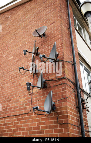 Array von alten und neuen Satelliten-TV-Empfänger Gerichte auf der Wand einer Wohnung mehrfamilienhaus Maryport Cumbria England Großbritannien Stockfoto