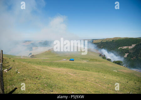 Aberystwyth Wales UK, 27. Juni 2018 Deutschland Wetter: ein Waldbrand, der gestern gestartet ist noch immer tobt, der die steilen Hänge des Rheidol Valley, einige Kilometer landeinwärts von Aberystwyth in Mid Wales. Das Gelände ist es für die Feuerwehr unmöglich - Mannschaften ihre Fahrzeuge zu erhalten, schließen Sie auf die Flammen, und das Feuer wird von einem Fachmann Hubschrauberbesatzung, die Fallen sind Tonnen von Wasser behandelt, geschöpft aus dem Fluss auf die brennenden Bäume. Photo Credit: Keith Morris/Alamy leben Nachrichten Stockfoto