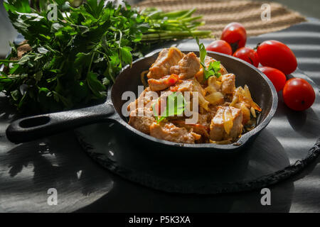 Fisch Chinooklachse sauteed mit Gemüse, Tomaten, Zwiebeln und Gewürzen in einer gusseisernen Pfanne rustikal Stockfoto