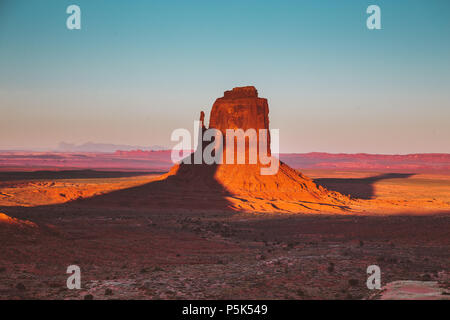 Klassische Ansicht der berühmten Monument Valley mit Schatten des Westens Mitten auf dem Osten Mitten im schönen goldenen Abendlicht bei Sonnenuntergang geworfen werden, Arizona Stockfoto