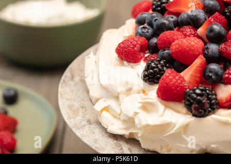 Pavlova baiser Kuchen Dessert mit Erdbeeren, Brombeeren, Himbeeren und Heidelbeeren, auf einem Granit Plattform gepflanzt Stockfoto