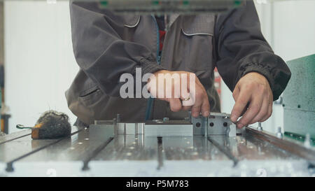 Arbeitnehmer mit einem Schaber Anfasen entfernen Grate an der Gegenstand aus Metall für die Herstellung von industriellen CNC-Maschinen Stockfoto